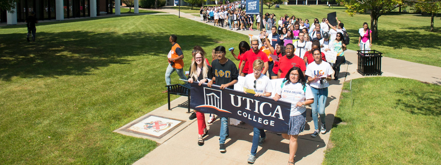 group of Utica college students marching down walkway with signs