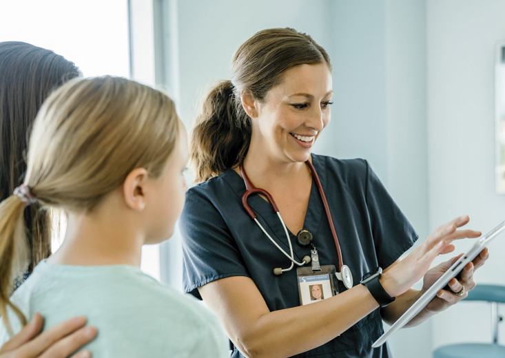 nurse showing information to parent of pediatric patient